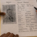 Researchers review the 1921 Baltimore death certificate of Daniel Newman documenting his burial at Laurel Cemetery.