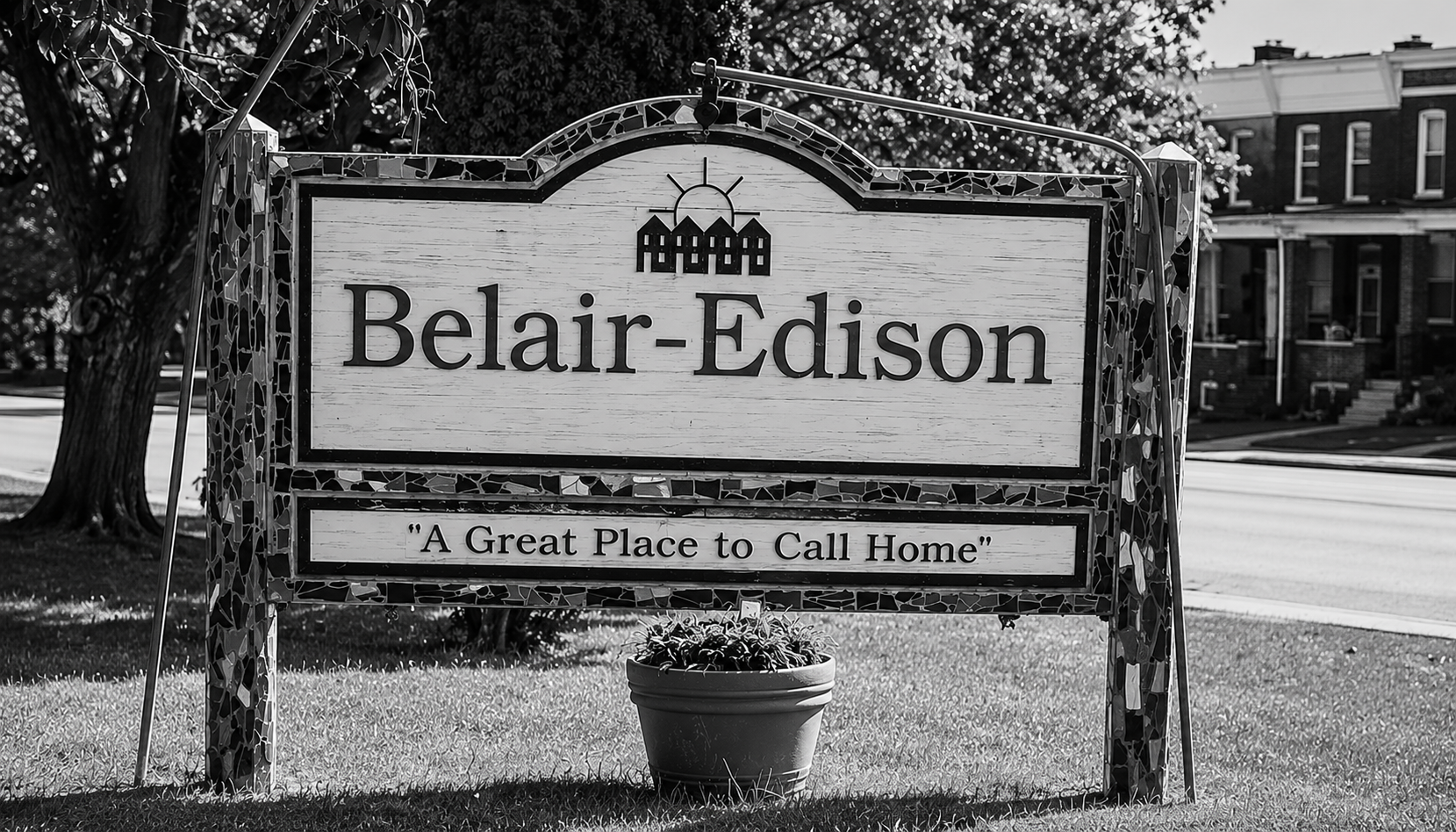 Black-and-white photograph of the Belair-Edison neighborhood entrance sign in Baltimore, with trees and rowhouses in the background.