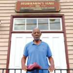 A man stands in front of the historic Fishermen's Hall building in Baltimore.